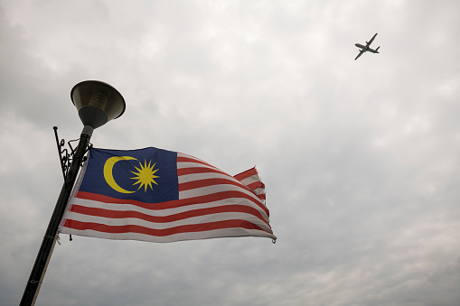 A Malaysian flag blows in the breeze as a plane descends for landing in Kota Kinabalu, Malaysia