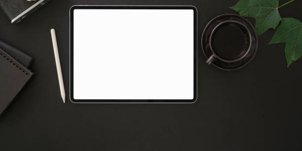 istock Top view of modern workplace with blank screen digital tablet and black coffee cup on dark table 1194395121