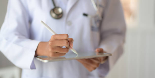 istock Cropped shot of young doctor checking patient chart while using digital tablet 1194395897