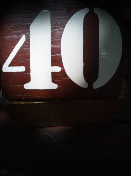 istock Alphabet, number 40 white, on a brown wooden background with specific light 1194399329