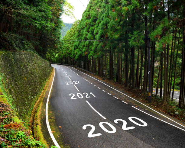 2020 to 2043 on highway and white marking lines in the forest stock photo