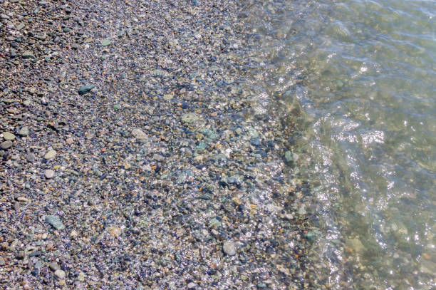istock pebble coastline. Seashore  with transparent water and small stones 1194411333