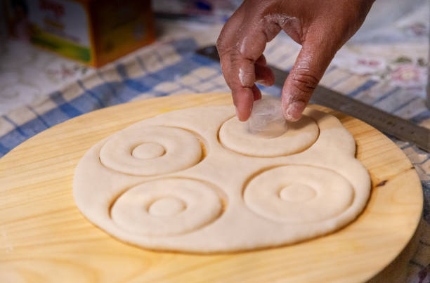 Lady preparing Donuts shapes. Closeup macro raw homemade dough for donuts preparation kept ready for deep fry.