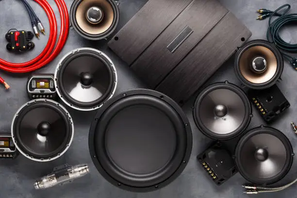 Photo of car audio, car speakers, subwoofer and accessories for tuning. Dark background. Top view.