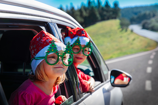 christmas car travel- happy boy and girl travel in winter, family christmas vacation