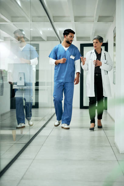 Off to save more lives Shot of two medical practitioners walking through a corridor in a hospital medical occupation stock pictures, royalty-free photos & images