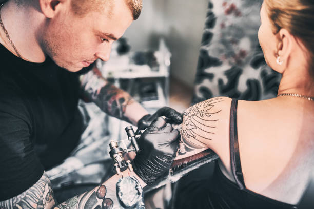 istock Tattoo Artist making a tattoo on a customer's shoulder 1194427106