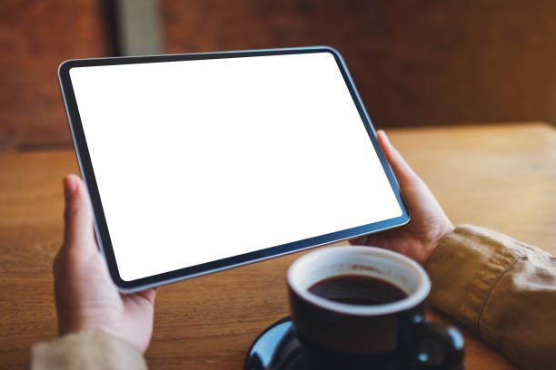 istock a woman holding black tablet pc with blank white screen with coffee cup on wooden table 1194428309