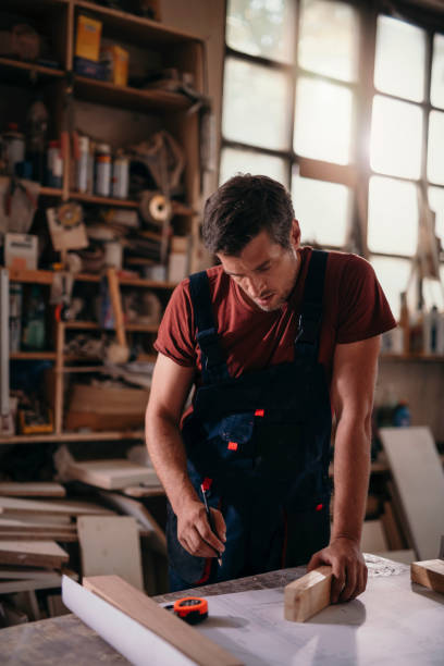 istock Young carpenter analyzing design plans while making furniture in a workshop. 1194429938