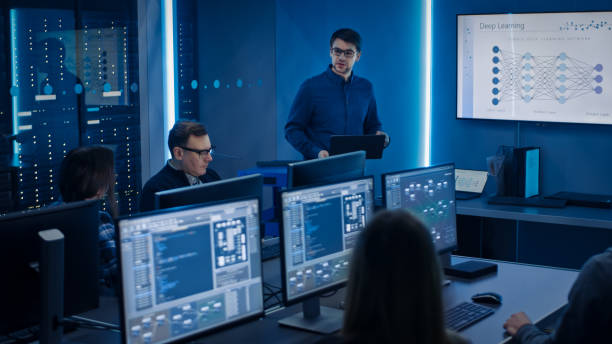 istock Team of Professional IT Developers Have a Meeting, Speaker Talks about New Blockchain Based Software Development Shown on TV. Concept: Deep Learning, Artificial Intelligence, Data Mining, Neural Network 1194430832