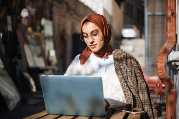 istock Young woman sitting at sidewalk cafe and using Laptop 1194432444