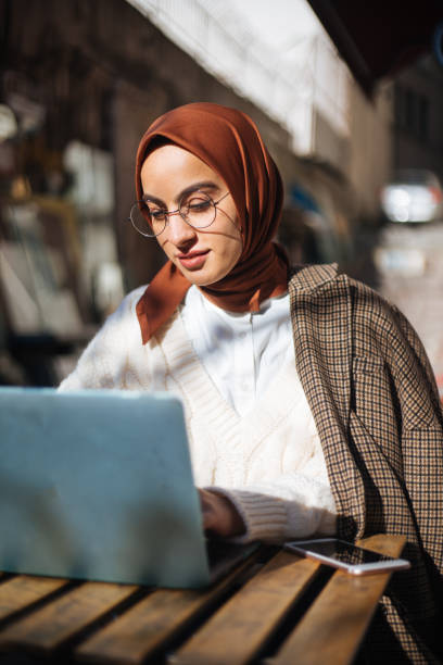 istock Young woman sitting at sidewalk cafe and using Laptop 1194432449
