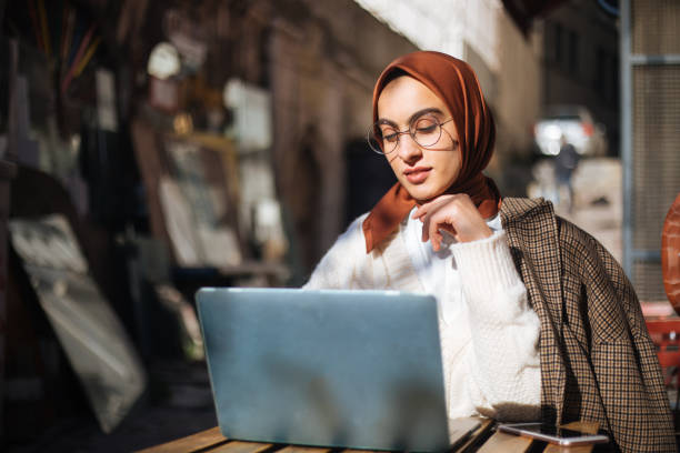 istock Young woman sitting at sidewalk cafe and using Laptop 1194432496
