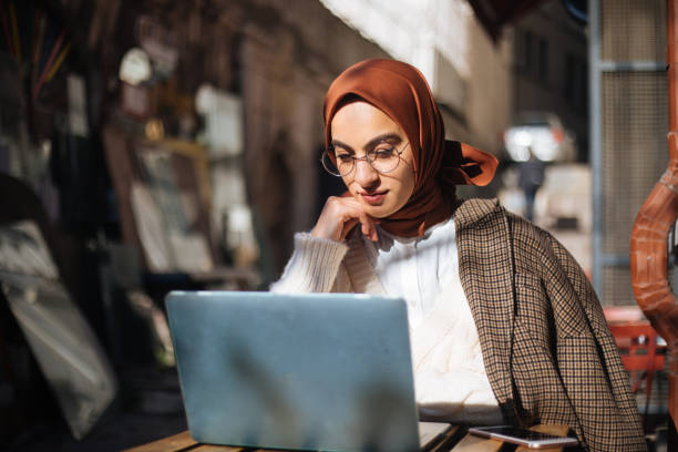 istock Young woman sitting at sidewalk cafe and using Laptop 1194432714