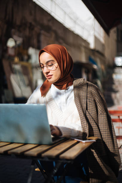 istock Young woman sitting at sidewalk cafe and using Laptop 1194432753
