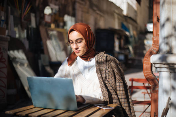 istock Young woman sitting at sidewalk cafe and using Laptop 1194432773