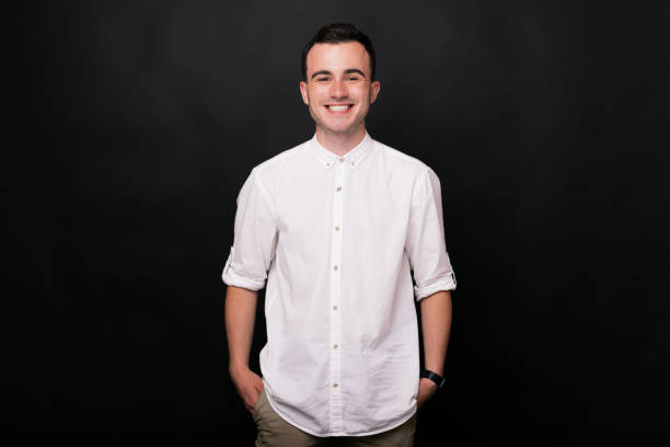 istock A young man is smiling at the camera on a black background. 1194435066