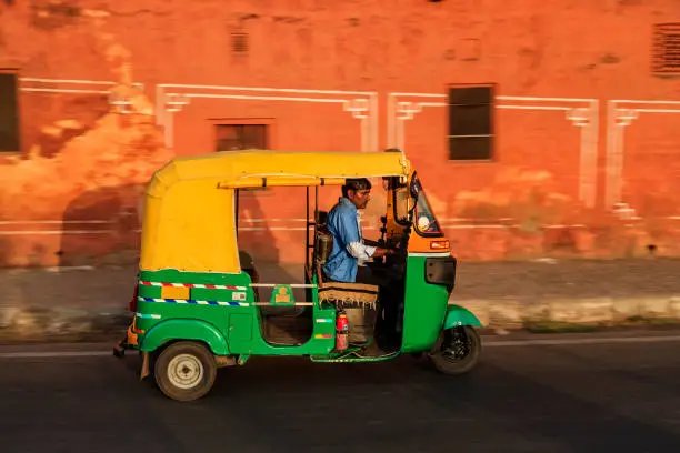 Indian man drives auto rickshaw (tuk-tuk) on streets of Rajasthan, India.