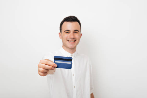 istock cheerful young man in white suit holds a card credit 1194435729