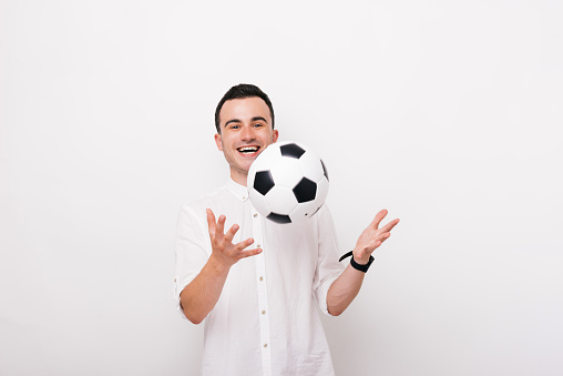 young man laughing, throwing a soccer ball and looking at the camera on white background