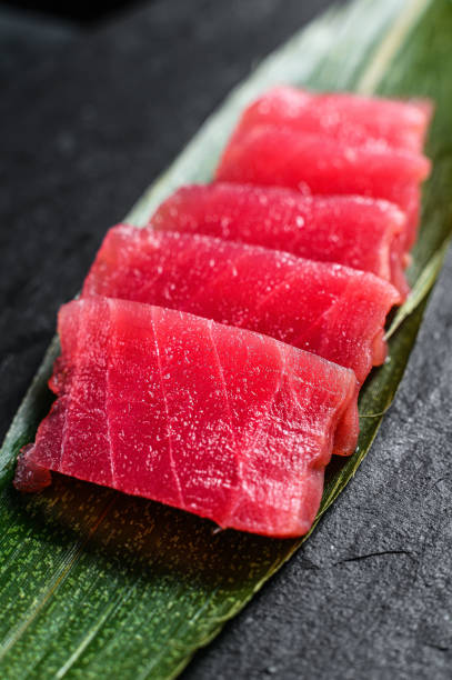 istock sashimi tuna on a stone Board. Black background. Top view. Close up 1194435812