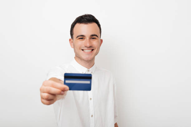 istock Young happy man holding a credit card on white background 1194435842