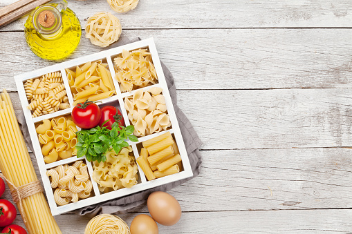 Various pasta in wooden box. Top view flat lay with copy space