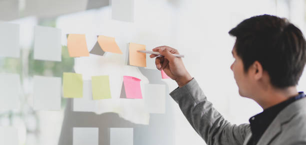 istock Young passionate businessman collecting the ideas from sticky note in modern office 1194436703