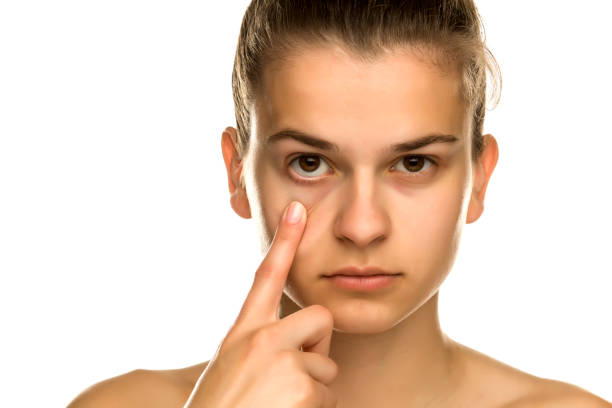 istock Young woman pulling her lower eyelid with her finger on white background 1194438901