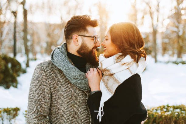 Potrait of a couple, having a winter walk, hugging on sunset lights stock photo