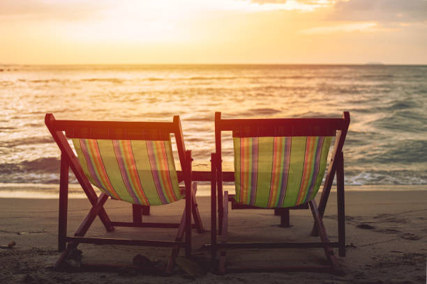 istock two blank beach bed chair set on the beach with sun twilight sky background. 1194440059