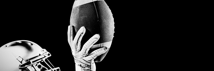 Side view of a Caucasian male American football playing wearing a helmet looking up and holding a football in one gloved hand