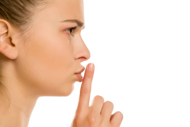 istock Young woman with finger on her lips on white background 1194440394