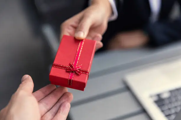 Photo of Business boss giving present gift box to office staff partner for job bonus concept.