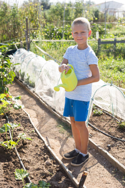 istock Little boy watering flower beds from a watering can 1194445292