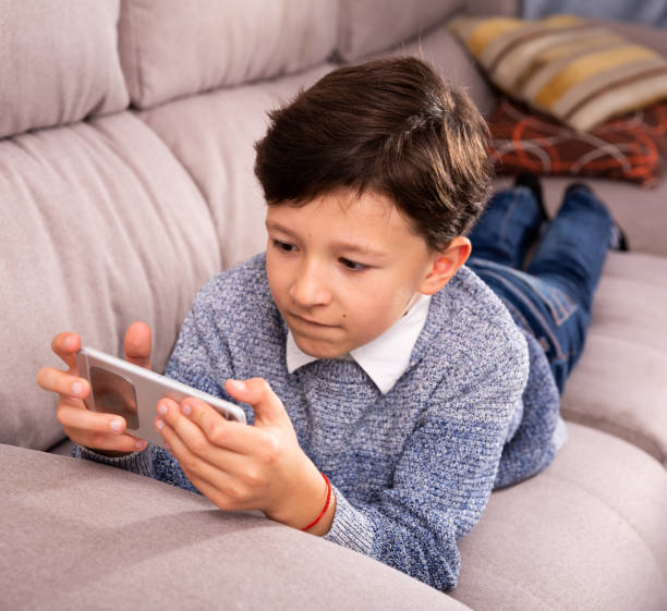 istock Preteen boy resting with smartphone on sofa at home 1194445968