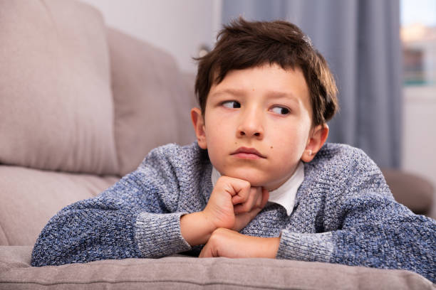istock Unhappy schoolboy sitting at sofa and thoughtful about  trouble 1194445971