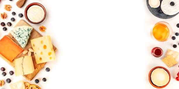 istock Cheese board, a flat lay panoramic top shot on a white background with copy space. Blue cheese, Leicester, Emmental, Brie, and others sorts with wine and fruits, forming a frame with a place for text 1194446310