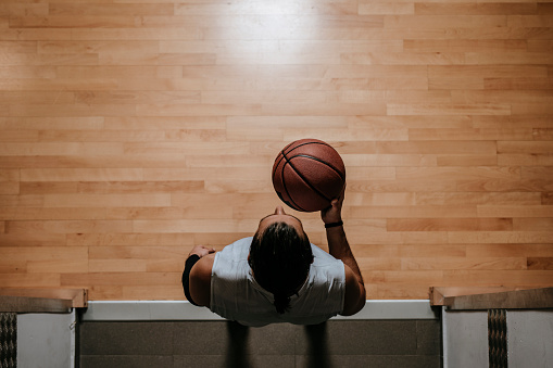 From above photo of basketball player standing on court and holding a ball.