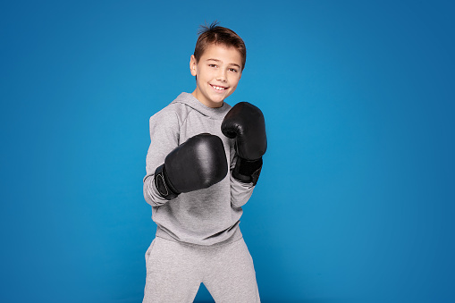 Young child sportsman in boxing gloves. Fitness, energy health. Sportswear fashion.