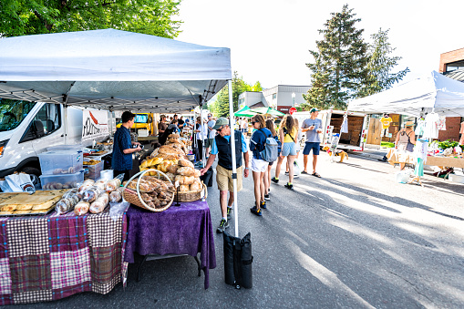 Aspen, USA - July 6, 2019: Vendors selling baked goods bread at stall stand in farmers market with people walking in outdoor summer street