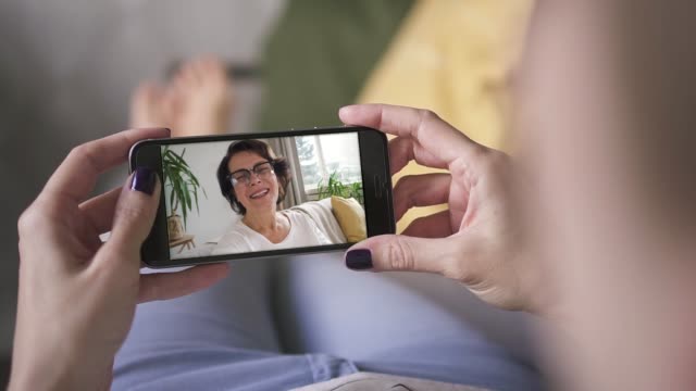 mother waving and blowing kiss to her daughter through smart phone video call