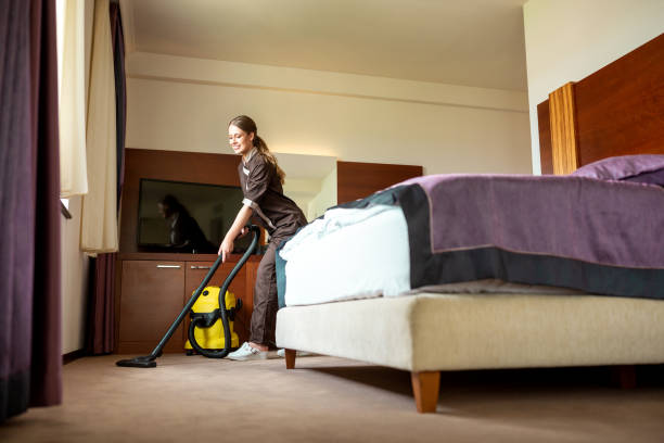 istock Room service lady vacuuming the guest room 1194457148