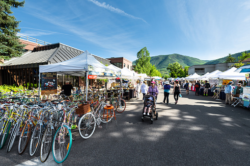 Aspen, USA - July 6, 2019: Vendors selling vintage bicycles at stall stand in farmers market with people walking in outdoor summer street