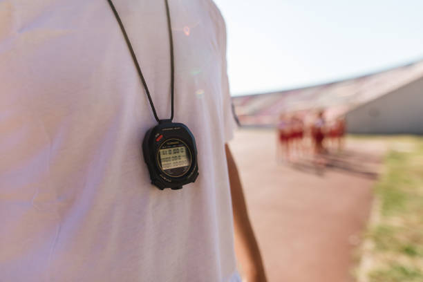 Coach holds a stopwatch to check the runners' speed statistics during practice. soft and selective focus.
