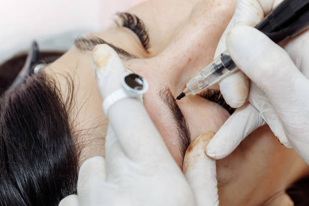 istock Permanent makeup, tattooing of eyebrows. Cosmetologist applying make up 1194464380
