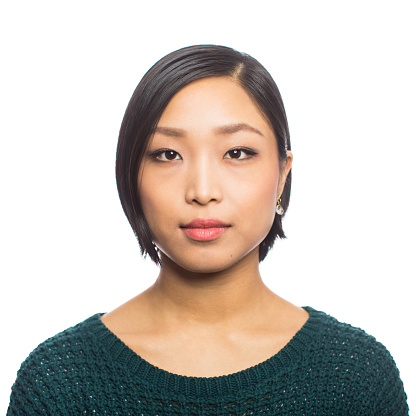 Close-up portrait of confident young asian woman staring at camera against white background. Shot of female with short hair looking at camera.