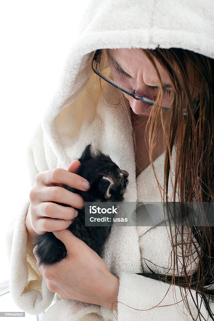 Young Woman is Speaking Her Kitten Young woman who's wearing robe is cuddling her closed eyes cute kitten.  Adult Stock Photo