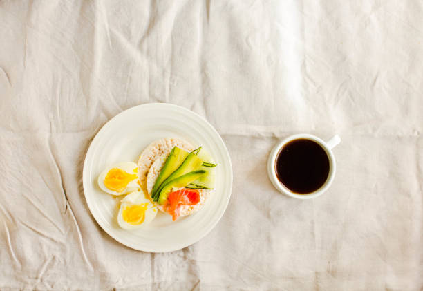 Rice crispy cakes with avocado and fresh salted salmon. Cup of coffee. Top view. Space for text. High protein and low carbohydrate meal stock photo