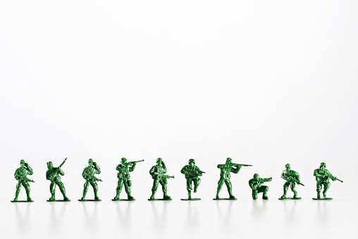 Plastic toy soldiers are standing in a row on a white background, ready for battle.